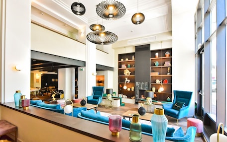 A modern hotel lobby with blue seating, decorative vases, and a fireplace.