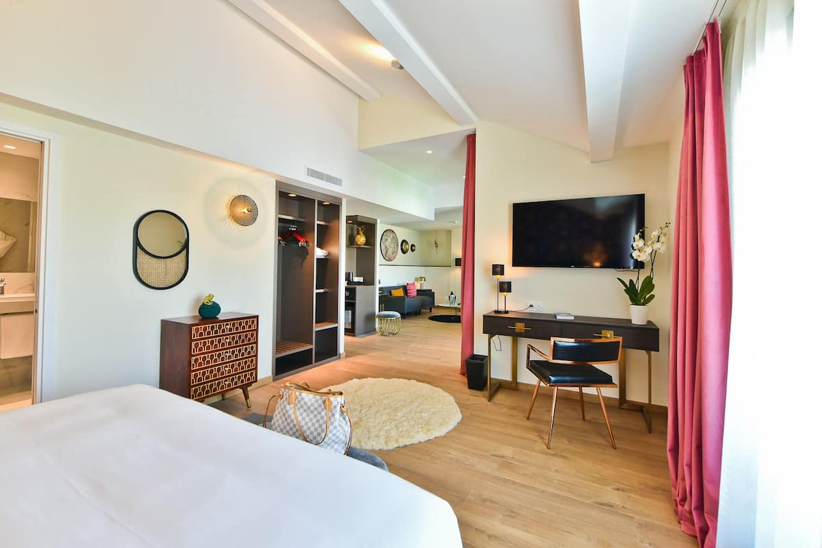 Una habitación de hotel moderna con una cama grande, un escritorio con una silla, un televisor y un armario.