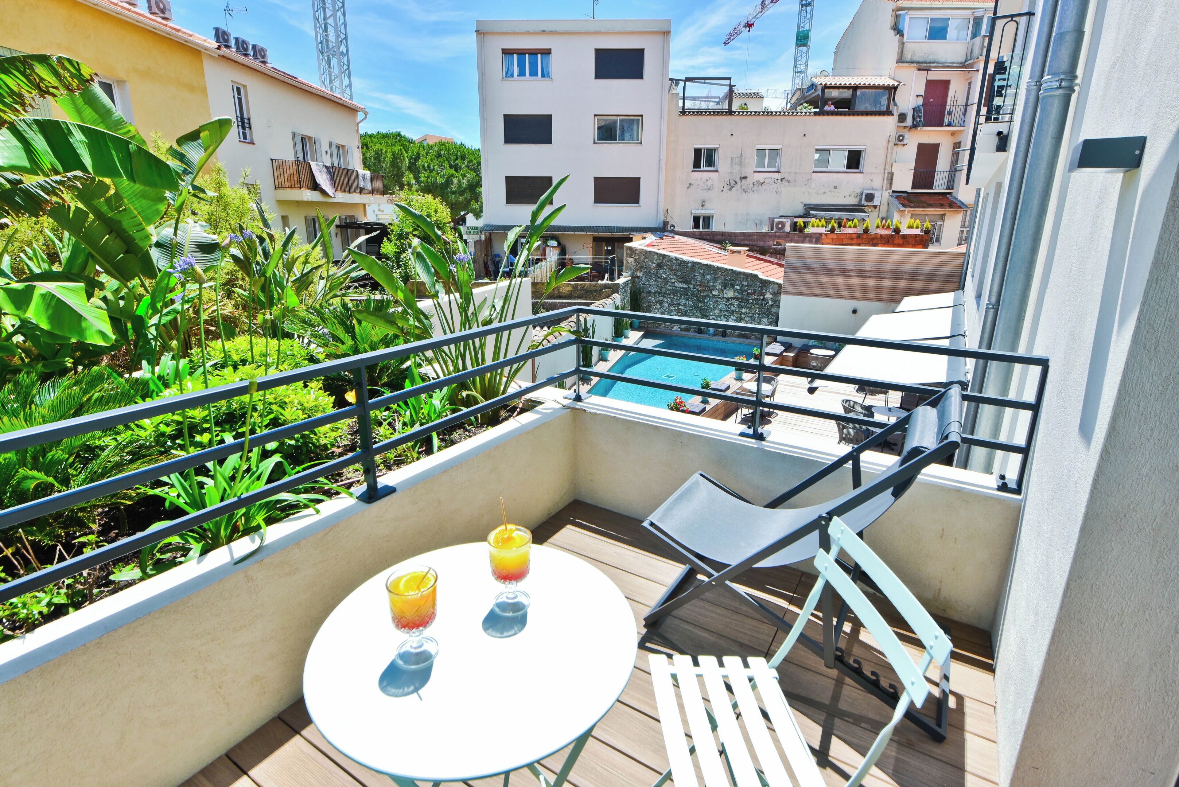 Ein Balkon mit Schwimmbad, zwei Gläser mit Getränken und einem Tisch.