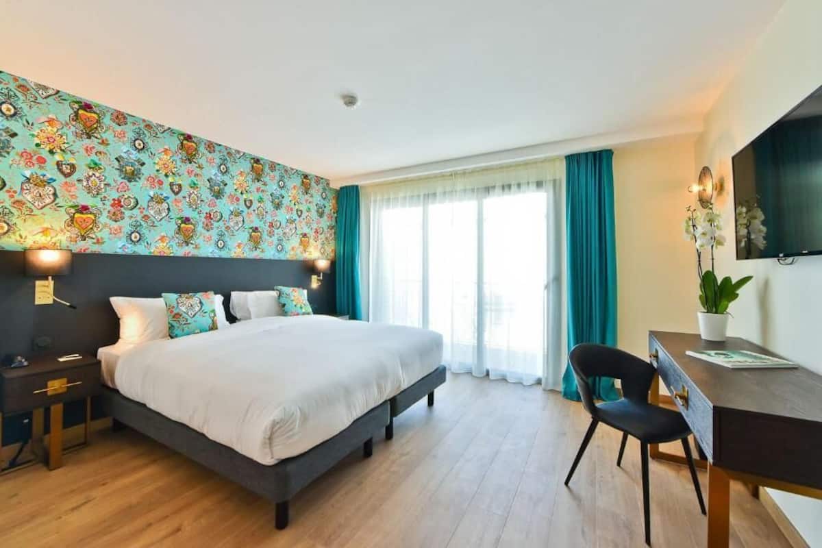 Una habitación de hotel moderna con una cama grande, un escritorio y un televisor.