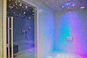 Un baño con paredes de mosaico y cabina de ducha de vidrio.