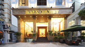 The entrance of Santa Luxury hotel with a grand facade, a staircase leading to the entrance, and outdoor seating area with potted plants. - Santa Luxury Hotel (Da Nang)