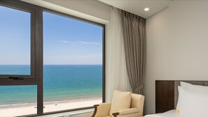 A hotel room with a large window offering a view of the beach and ocean. - Santa Luxury Hotel (Da Nang)
