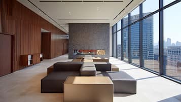Un interior moderno con asientos escalonados, chimenea y amplios ventanales que ofrecen vistas a la ciudad.