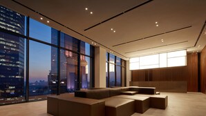 Un interior moderno con ventanas amplias, una zona de estar y vistas a un paisaje urbano al atardecer.