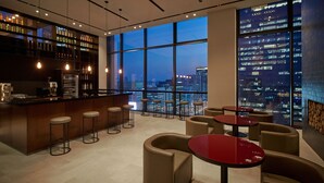 Zona de bar moderna con vista a la ciudad, que incluye barra, taburetes y mesas.