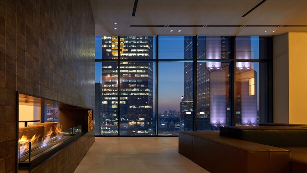 Un interior moderno con chimenea, zona de estar y ventanas amplias que ofrecen vistas a la ciudad.