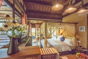 A room with a bed, a bedside table, a vase with flowers, and a window with curtains. - Guyue Caotang (Huzhou)