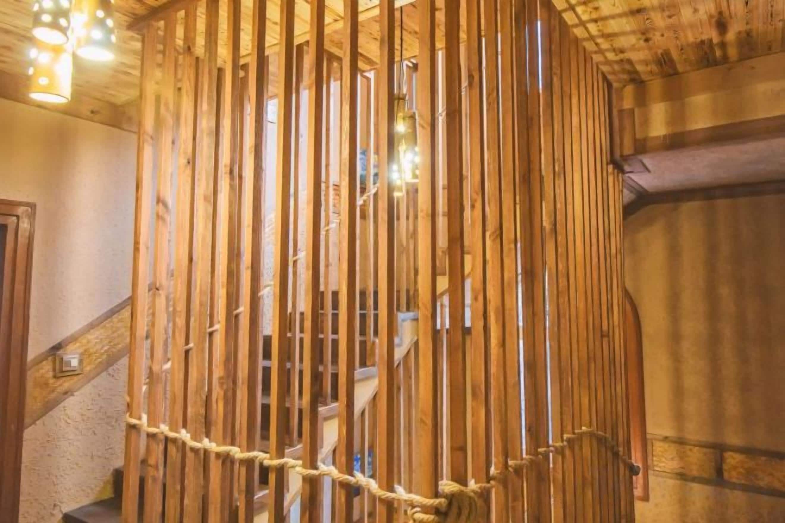 A wooden staircase with a rope barrier, wooden paneling, and a handrail.