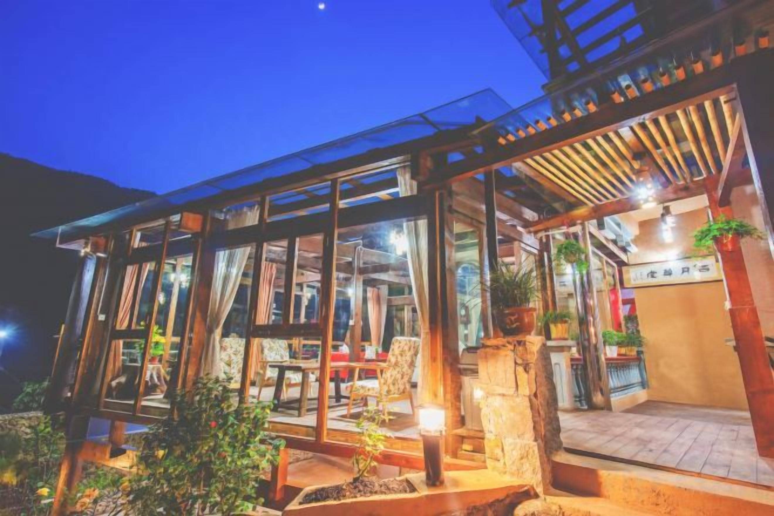 A glass-enclosed building with a wooden deck and outdoor seating area.