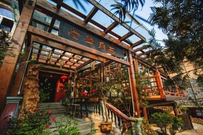 A traditional wooden building with a sign, a staircase, and potted plants.