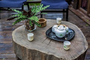 A rustic wooden table with a teapot, cups, and a potted plant. - Guyue Caotang (Huzhou)