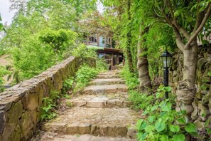 A stone staircase leading to a building surrounded by lush greenery. - Guyue Caotang (Huzhou)