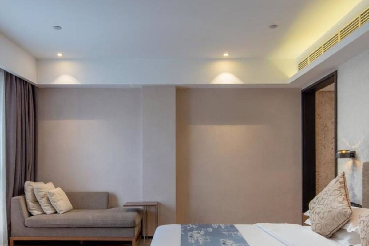 Een moderne slaapkamer met een bed, een slaapbank en een nachtkastje.