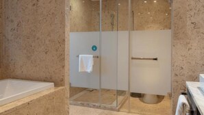 Une salle de bain moderne dotée d’une douche à parois de verre, d’une baignoire et d’un meuble-lavabo avec un porte-serviettes.