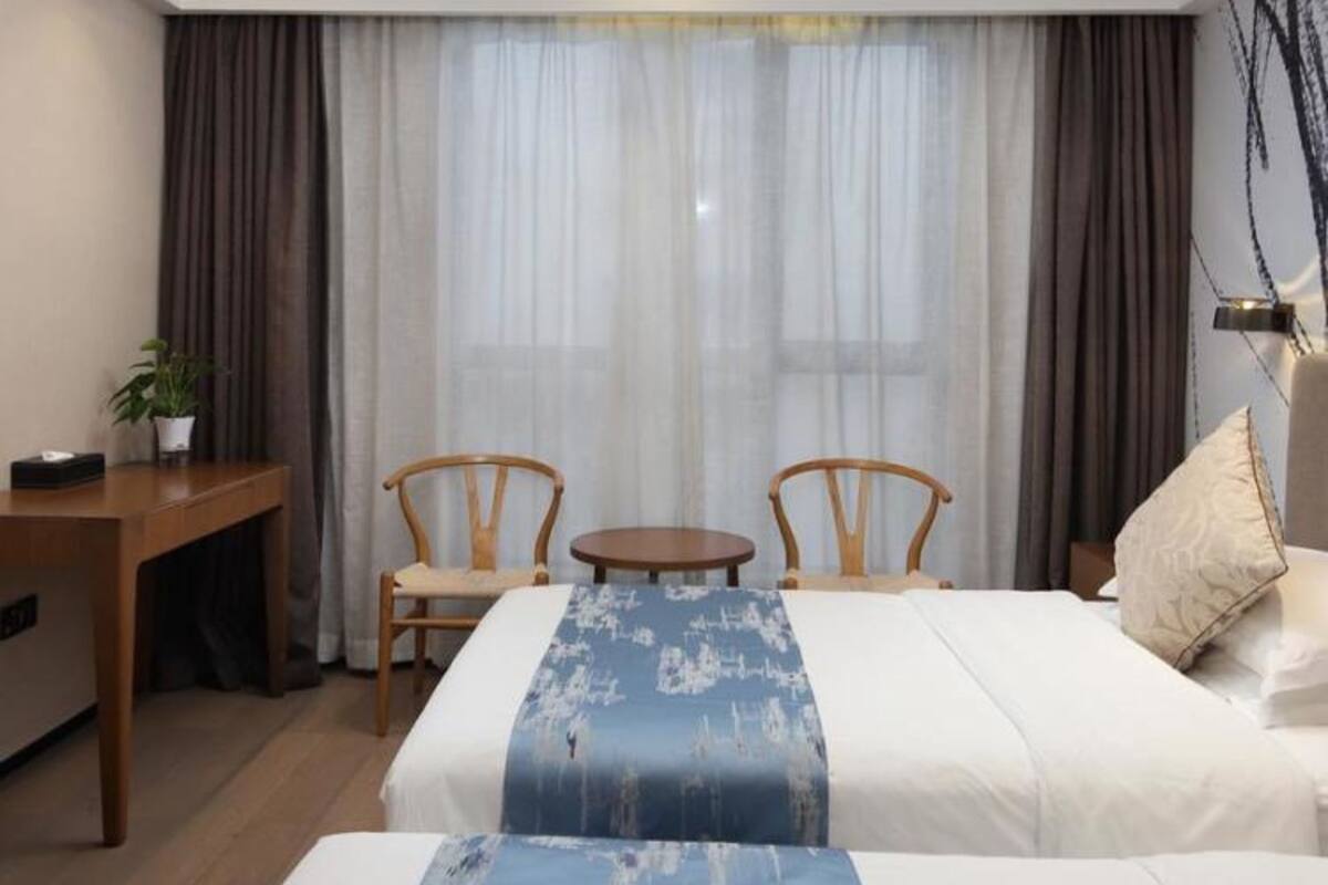 Een hotelkamer met twee bedden, een bureau, een stoel en een tafeltje.