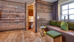 Ein modernes Zimmer mit Holzwandverkleidung, einer gepolsterten grünen Bank und einem kleinen runden Tisch.