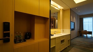 Un baño de hotel con lavamanos, espejo y cafetera en la encimera.