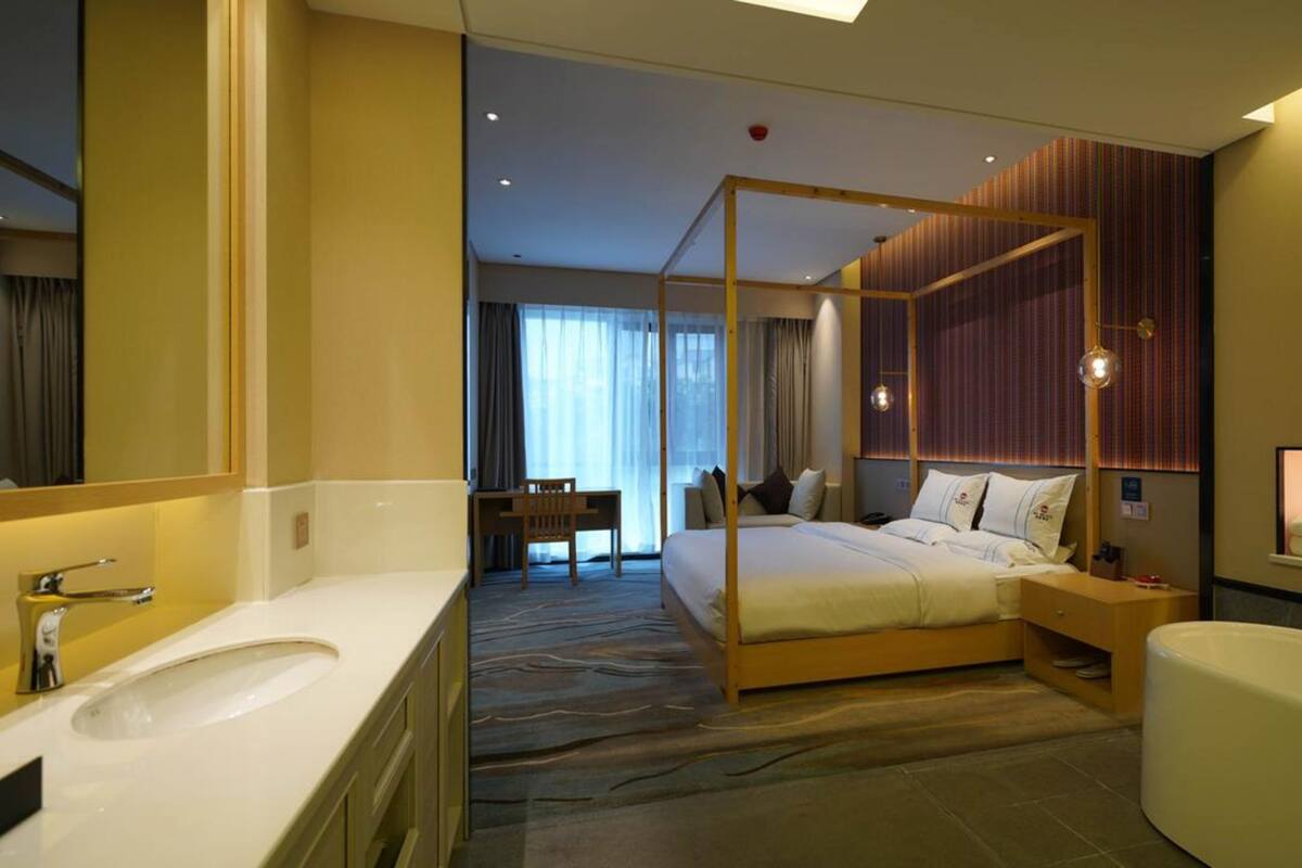 Een moderne hotelkamer met een groot bed, een eigen badkamer, een zithoek en uitzicht op de stad.
