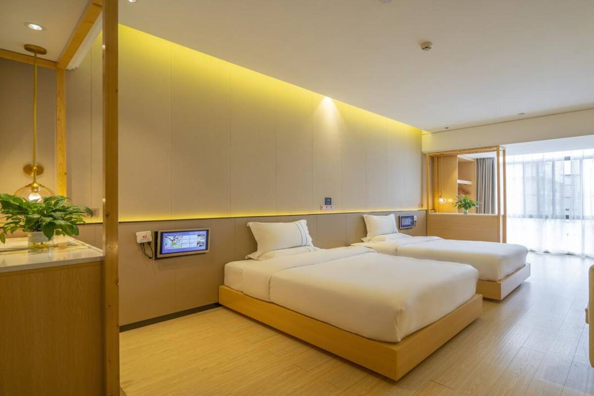 Een moderne hotelkamer met twee bedden, een bureau en een zithoek.