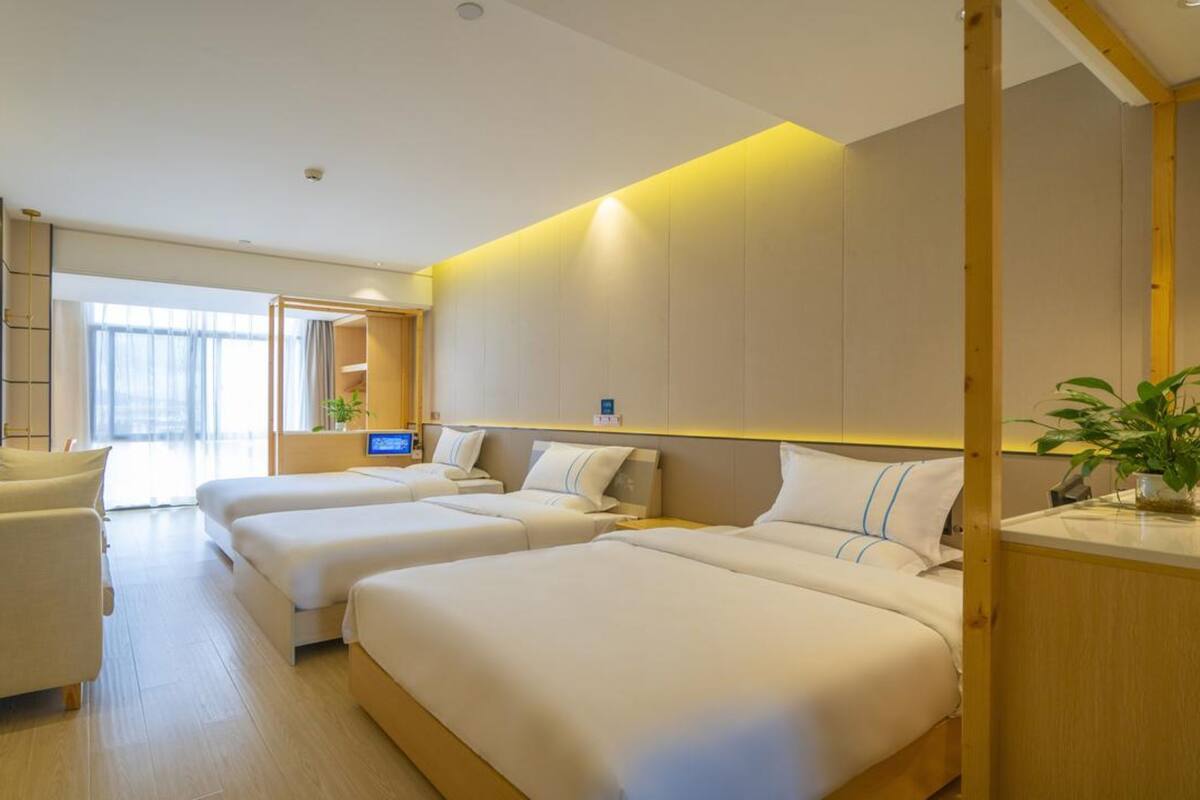 Een moderne hotelkamer met twee bedden, een bank, een bureau en een groot raam.