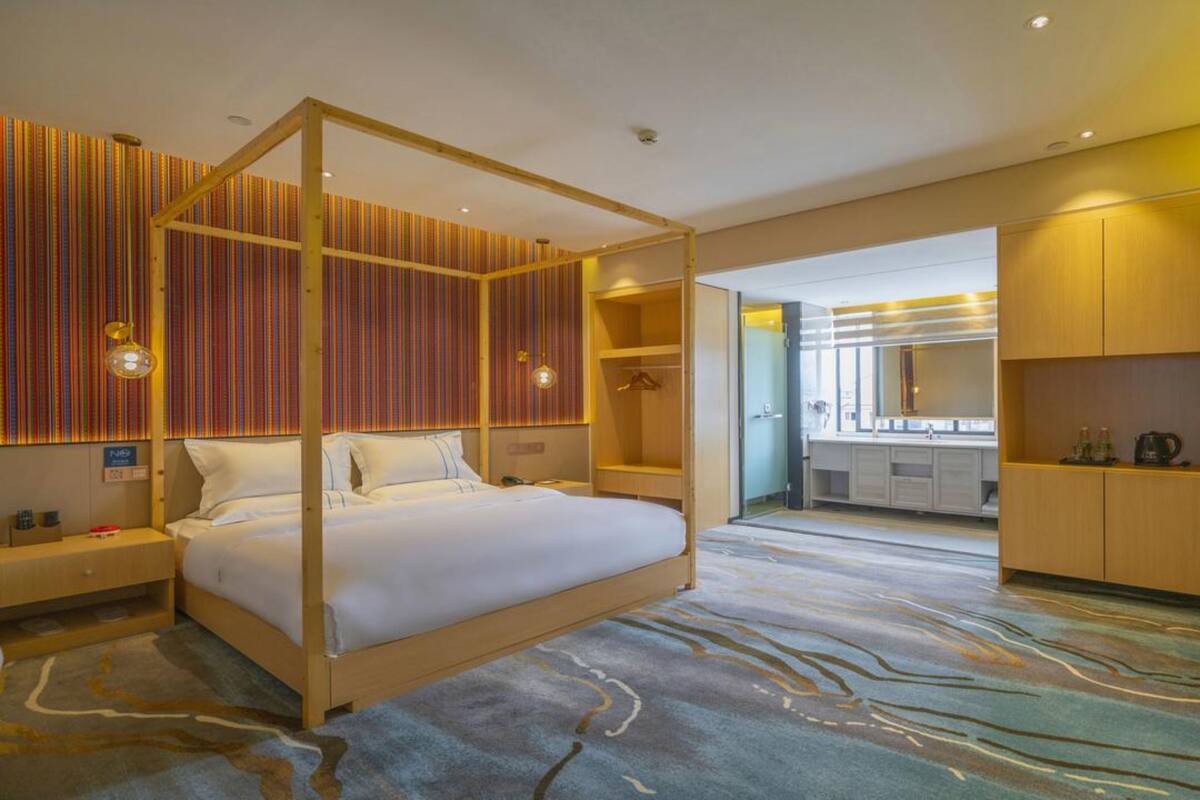 Een moderne hotelkamer met een hemelbed, inloopkast en een badkamer met een grote spiegel.
