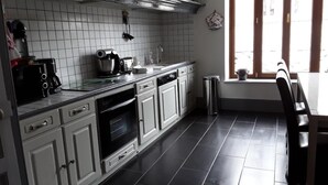 A kitchen with white cabinets, a black countertop, and a window with blinds.