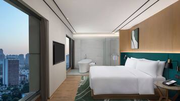 A modern hotel room with a large bed, a bathroom, and a city view.