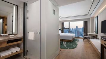 Une chambre d’hôtel moderne avec vue sur la ville, un grand lit, un bureau et un espace douche.