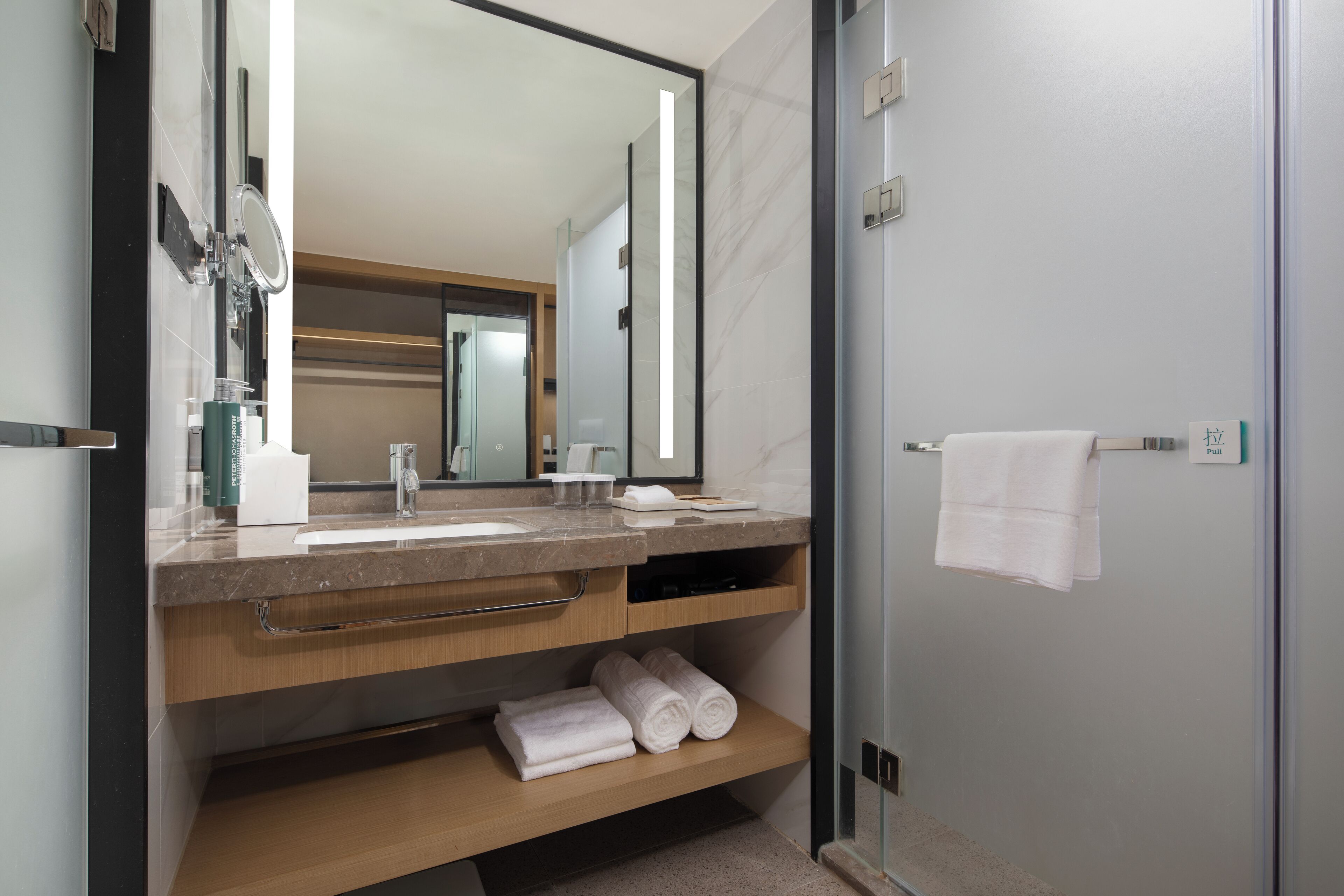 A modern bathroom with a large mirror, a sink, and a towel rack.