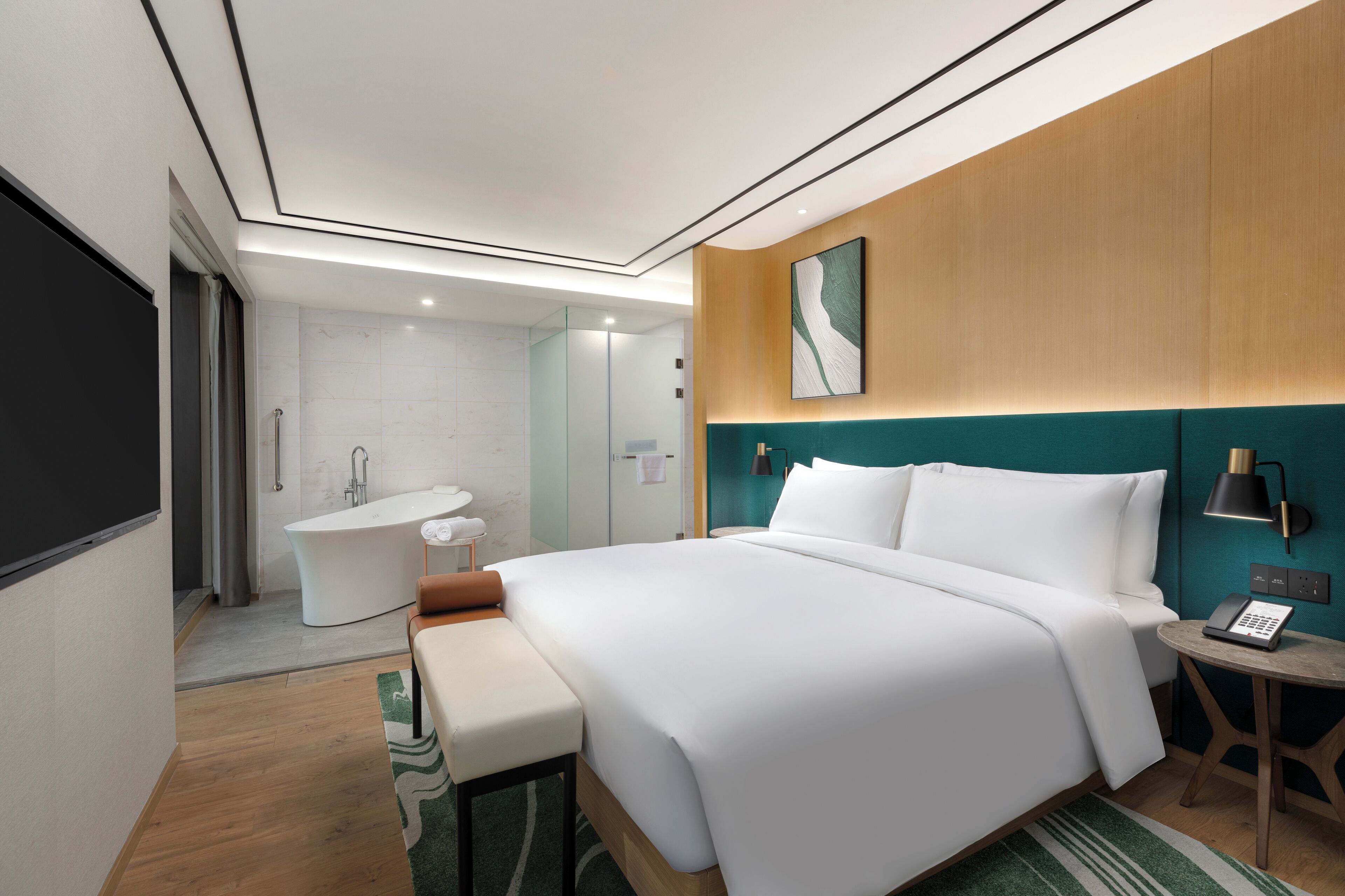 A modern hotel room with a large bed, a bathroom with a bathtub, and a view of the city.