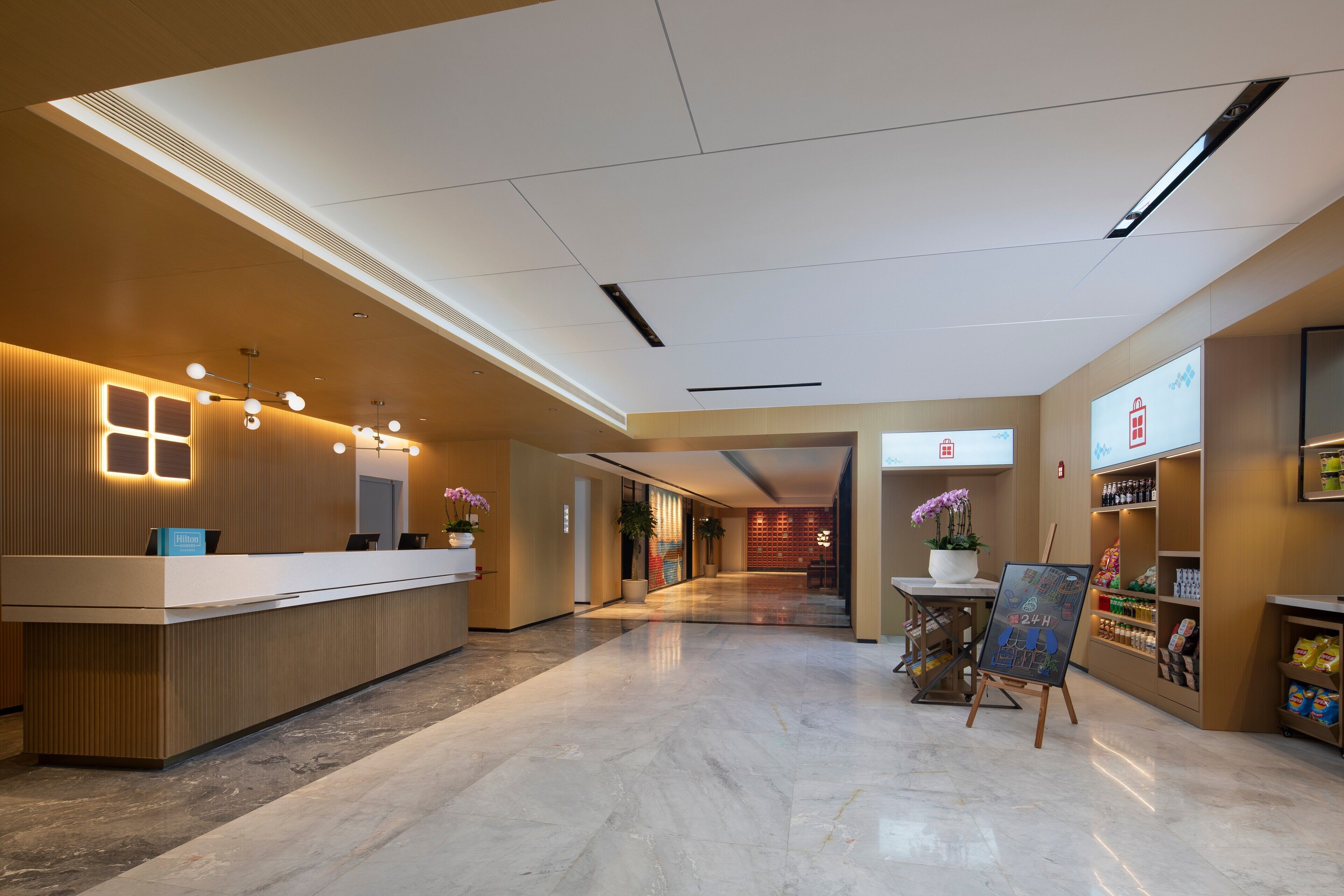 Een hotel receptiegebied met een modern ontwerp, met een receptiebalie, een zithoek met een kleine tafel en stoelen, en een prikbord.