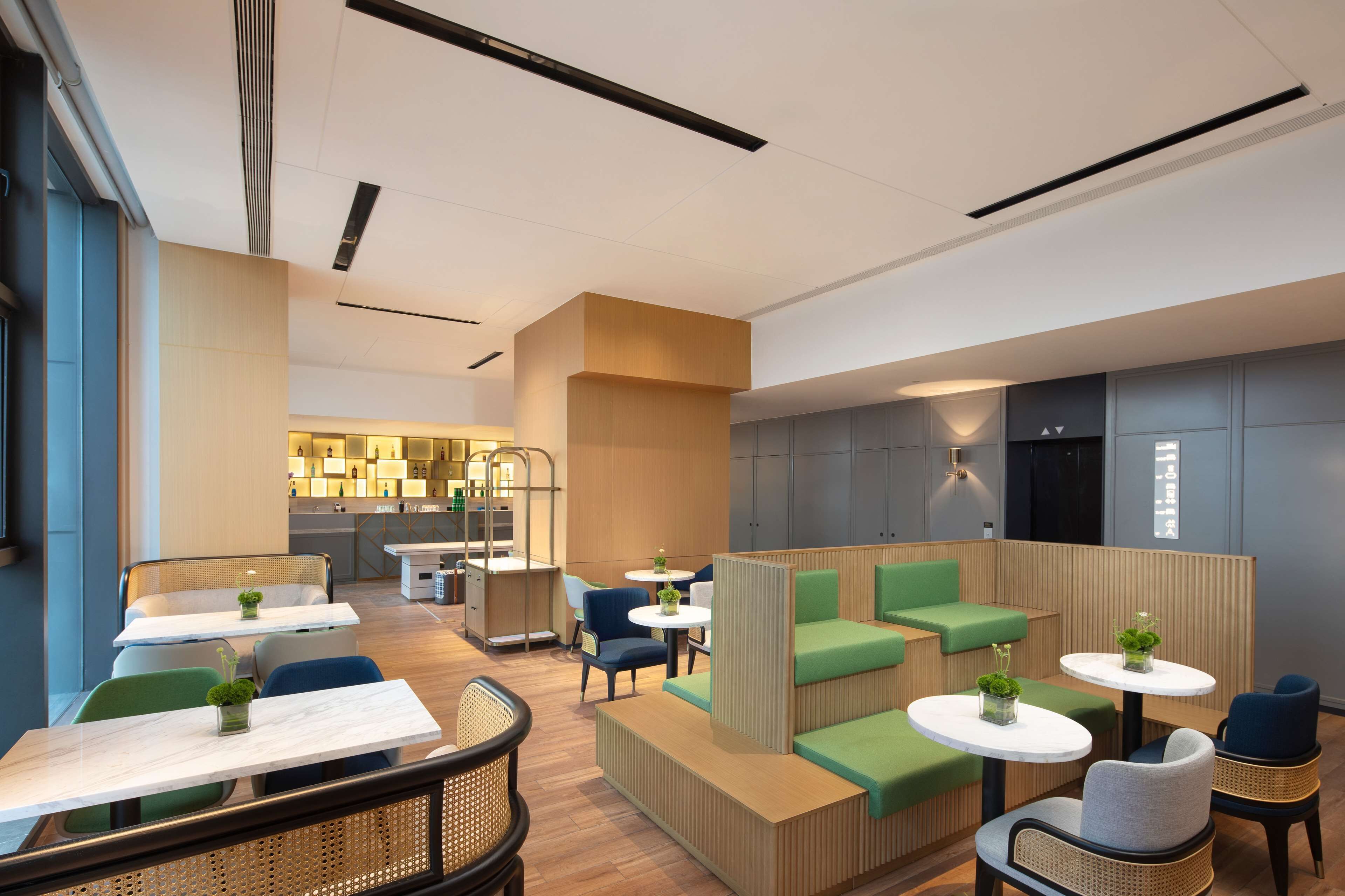 A modern interior with seating areas, tables, and a kitchen in the background.