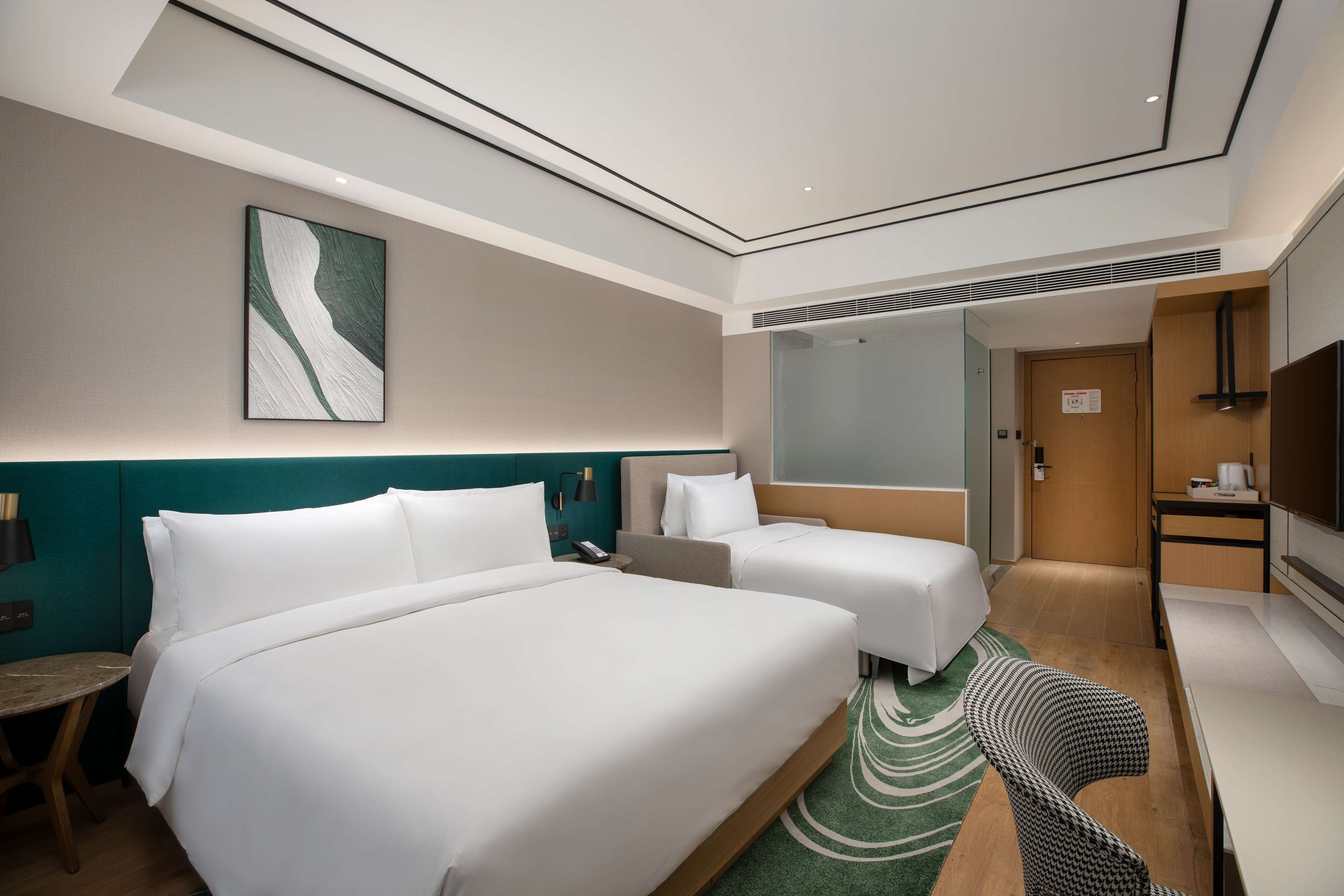 Une chambre d’hôtel avec deux lits, un bureau, une télévision et une salle de bain.