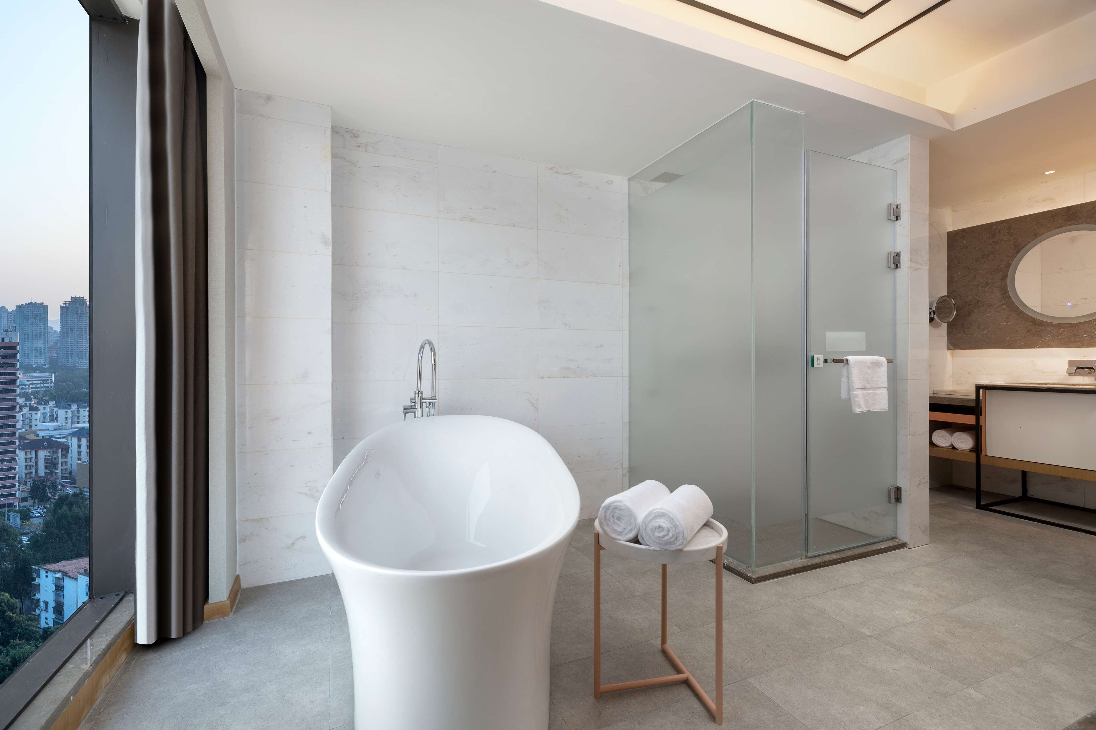 Une salle de bain moderne avec une baignoire sur pieds, une douche à parois de verre et un meuble-lavabo avec un miroir.
