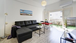 Ein modernes Wohnzimmer mit einer schwarzen Eckcouch, einem Glastisch und einem Essbereich mit roten Stühlen.