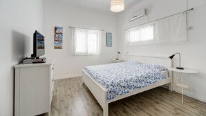 Ein Schlafzimmer mit Bett, Schreibtisch, Stuhl und einer Pendelleuchte.
