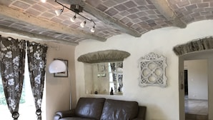 A room with a leather sofa, a table with a glass, a lamp, and a decorative mirror. - 12-person house with swimming pool, covered terrace, barbecue, shops nearby (Le Martinet)