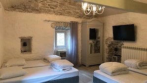 A room with two beds, a stone wall, a television, and a window with curtains. - 12-person house with swimming pool, covered terrace, barbecue, shops nearby (Le Martinet)