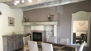 A dining area with a wooden table, four chairs, a fireplace, and a mirror reflecting the room. - 12-person house with swimming pool, covered terrace, barbecue, shops nearby (Le Martinet)