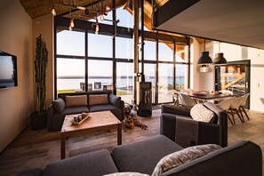 Un salon spacieux avec une grande fenêtre, une cheminée et un chien allongé sur le sol.