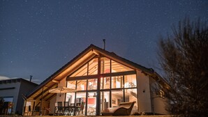 Une maison avec une grande fenêtre en verre, un toit et une pelouse.