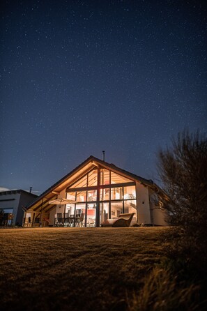 Une maison avec une grande fenêtre en verre, un toit et une pelouse.