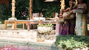 A traditional ceremony with participants around a water feature, including a stone basin and a wooden table with cushions. - Heavenly 3B/R Villa, Rice Field views & 10 min to popular Bali areas (seminyak)