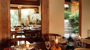A dining area with a wooden table set for two, surrounded by chairs, with a candle and a bottle on the table. - Heavenly 3B/R Villa, Rice Field views & 10 min to popular Bali areas (seminyak)