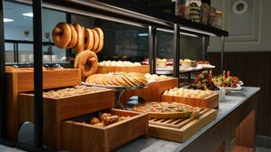 Un bufé con diversos productos horneados y pasteles expuestos en cajas de madera y sobre un soporte metálico.