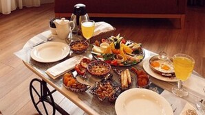 Una mesa de madera con platos, cubiertos y una variedad de alimentos para el desayuno.