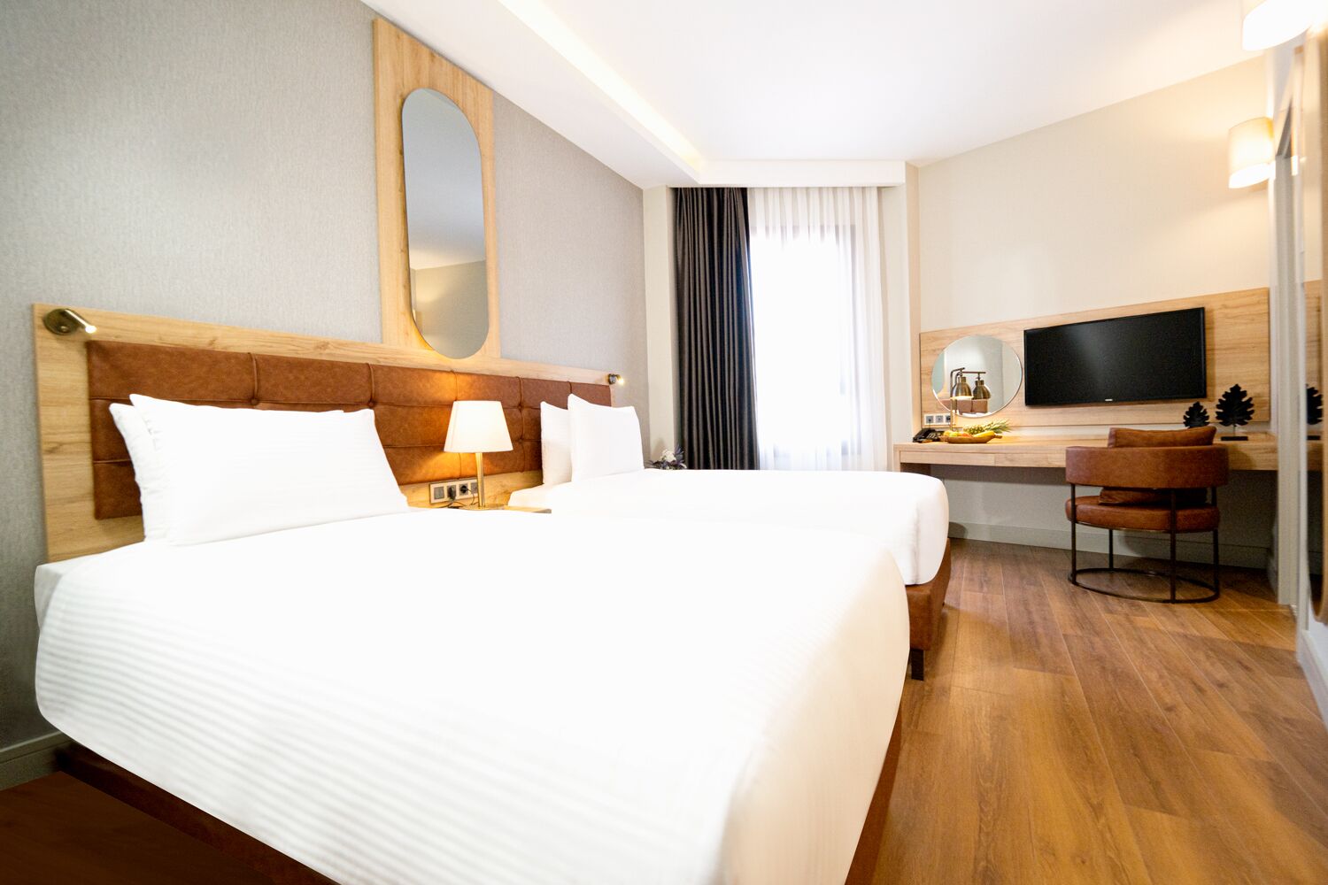 Habitación de hotel con una cama grande, un escritorio con televisor y una silla.
