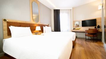 Habitación de hotel con una cama grande, un escritorio con televisor y una silla.
