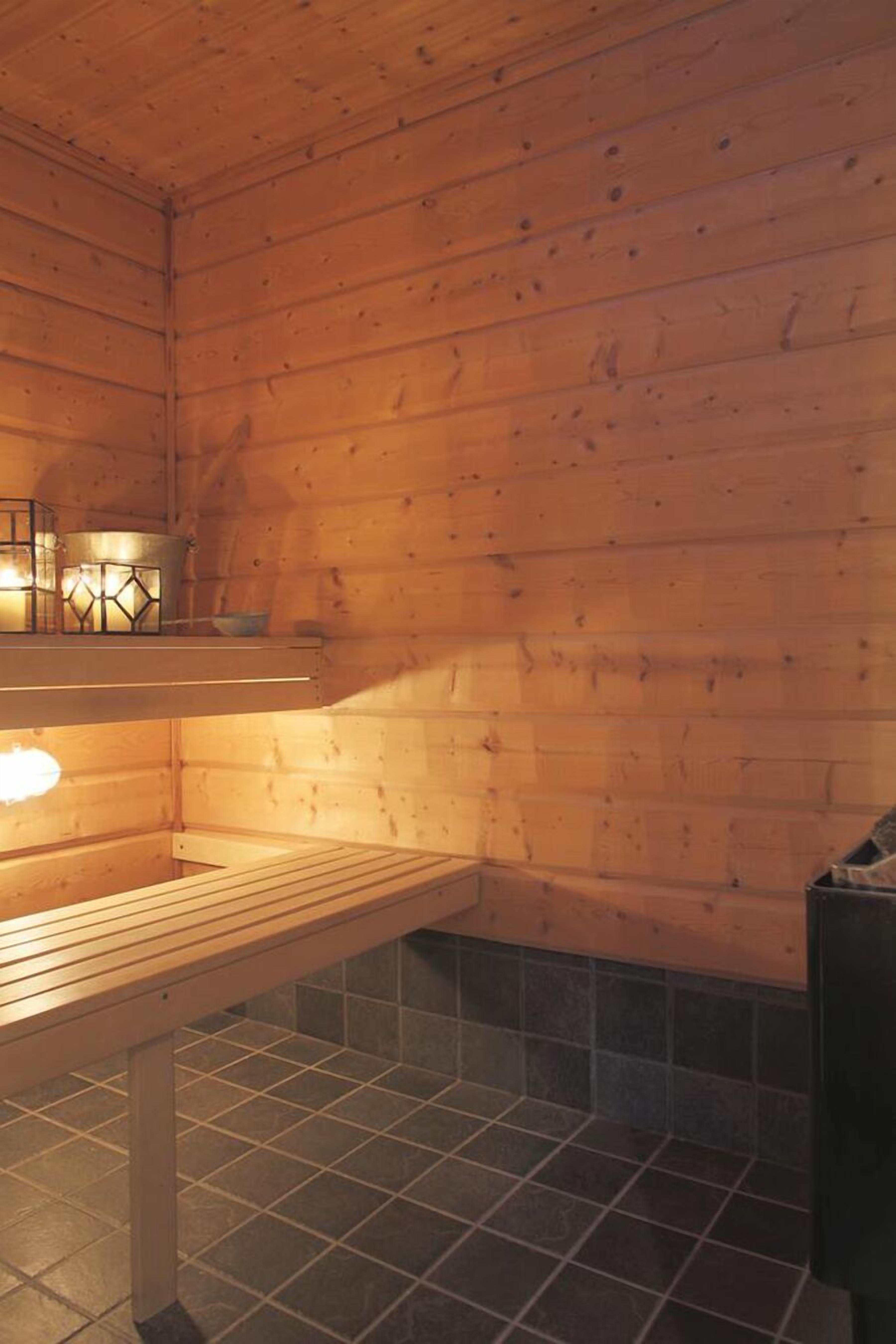 Un cuarto de sauna con paredes de madera, un banco y piso de baldosas.